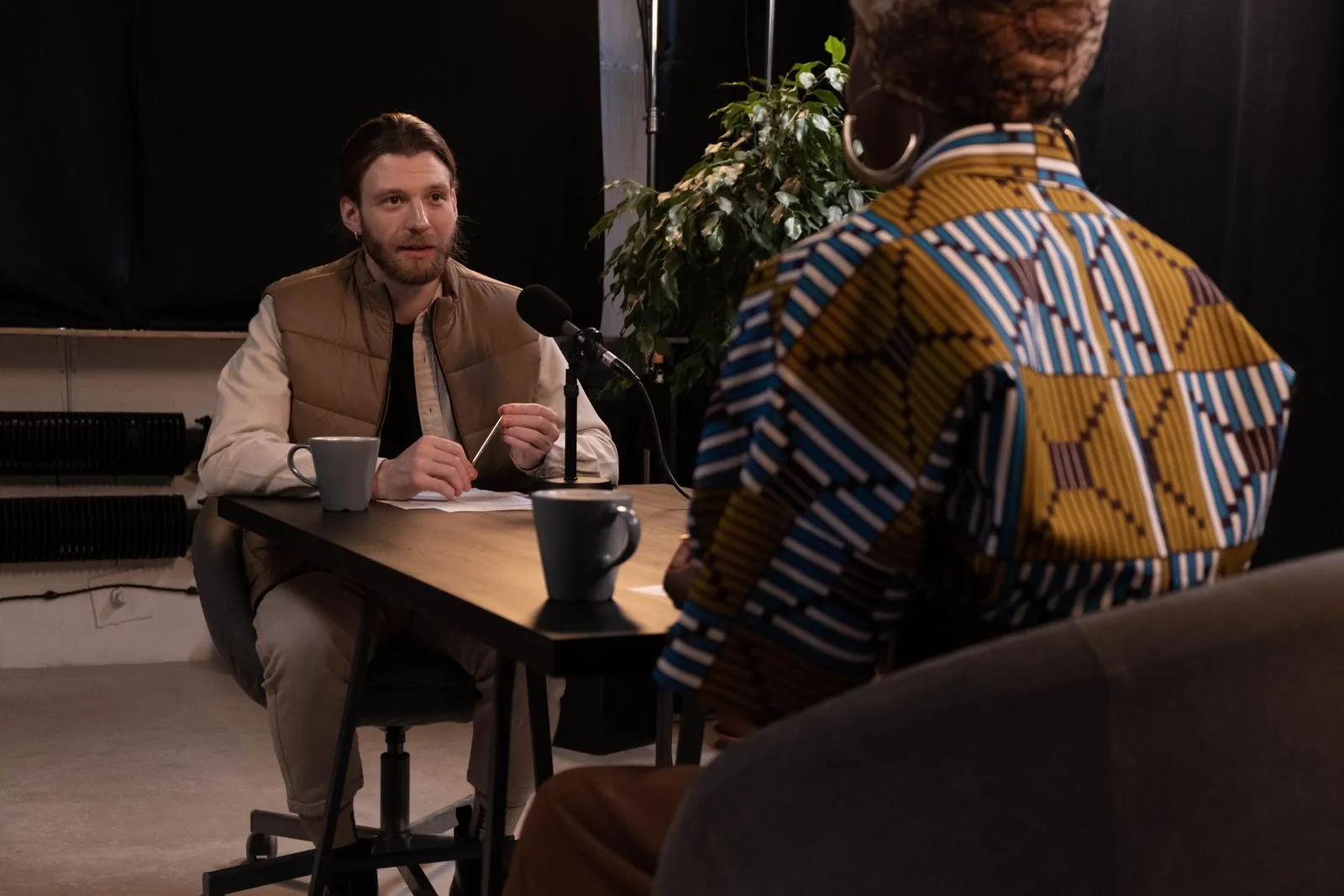 A podcast interview featuring diverse hosts in a professional studio setting with microphones and coffee mugs.
